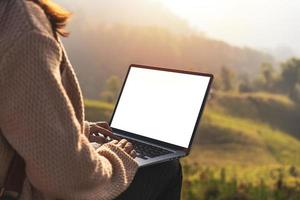 jeune femme voyageuse indépendante travaillant en ligne à l'aide d'un ordinateur portable et profitant du magnifique paysage naturel avec vue sur la montagne au lever du soleil photo