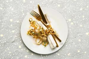 concept de dîner de noël. vue de dessus des couverts dorés sur une assiette avec des flocons de neige et des lumières de noël photo