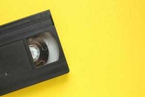 cassette de magnétoscope vhs noire sur fond jaune. ancienne technologie obsolète pour l'enregistrement sur bande et le visionnage de films multimédias. rétro, vintage, histoire, concept de nostalgie. vue de dessus, mise à plat photo