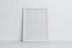 maquette de cadre photo blanc appuyé contre le mur. surface propre et vierge pour la présentation d'art