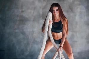 jeune femme de remise en forme avec un type de corps mince et en vêtements sportifs noirs est dans la salle de gym photo