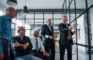 travailler avec des autocollants sur verre. une équipe âgée d'architectes d'hommes d'affaires âgés se réunit au bureau photo