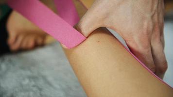 un médecin aide une femme par un traitement des jambes avec du ruban kinesio photo