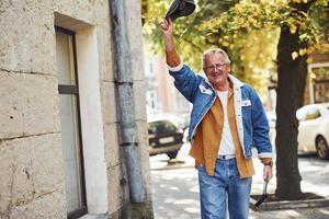 senior élégant dans des vêtements à la mode et des lunettes se promener dans la ville photo