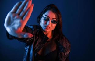 brune chaude à lunettes de soleil posant en studio avec éclairage au néon photo