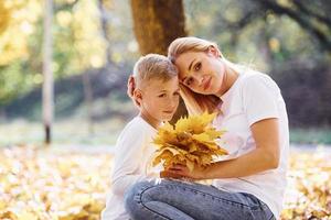 mère avec fils se reposer dans un magnifique parc d'automne aux beaux jours photo