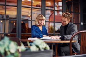 travailler avec des documents. jeune homme en vêtements formels a une conversation d'affaires avec une vieille femme au café photo