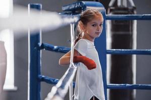 sur le ring de boxe. jeune petite fille en tenue de sport est dans la salle de gym a une journée d'exercice photo