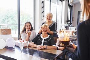 femme âgée avec famille et amis célébrant un anniversaire à l'intérieur photo