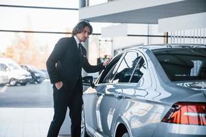 portrait d'un beau jeune homme d'affaires en costume noir et cravate près d'une nouvelle voiture moderne photo