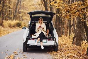 la fille est assise à l'arrière de la voiture. automobile neuve et moderne dans la forêt photo