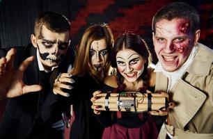 des amis avec une bombe dans les mains participent à la fête d'halloween thématique dans un maquillage et des costumes effrayants photo