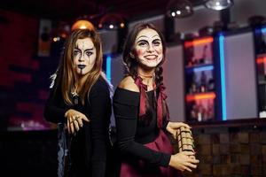 deux amies sont à la fête thématique d'halloween dans un maquillage effrayant et des costumes avec une bombe à retardement photo