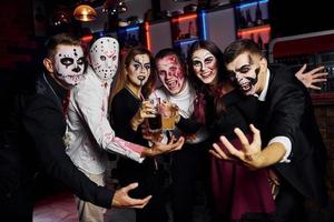 posant pour la caméra. les amis sont à la fête d'halloween thématique avec un maquillage et des costumes effrayants photo