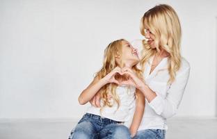 mère avec sa fille montre ensemble un geste d'amour dans le studio avec un fond blanc photo