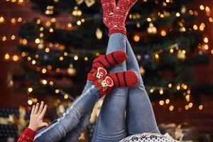 mère avec sa petite fille allongée sur le sol à l'intérieur dans des vêtements de fête pendant les vacances de noël photo