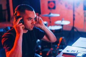 ingénieur du son dans les écouteurs travaillant et mélangeant de la musique à l'intérieur du studio photo