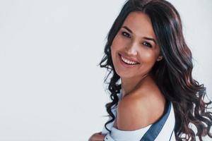 jeune brune en blouse blanche assise sur le lit dans la chambre blanche photo