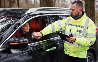 un policier en uniforme vert refuse de recevoir un pot-de-vin d'une femme dans un véhicule photo