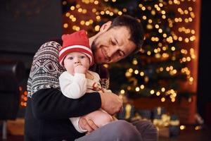 père avec son enfant ensemble dans une chambre décorée de noël photo