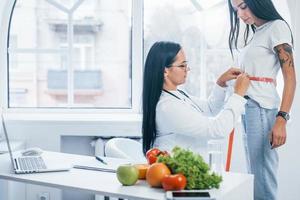 nutritionniste féminine mesurant la taille du patient par bande à l'intérieur du bureau photo