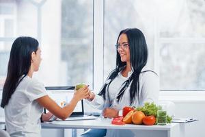 une nutritionniste avec un ordinateur portable donne une consultation au patient à l'intérieur du bureau photo