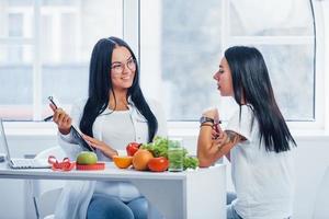 une nutritionniste donne une consultation au patient à l'intérieur du bureau en utilisant un bloc-notes photo