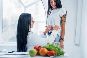 nutritionniste féminine mesurant la taille du patient par bande à l'intérieur du bureau photo