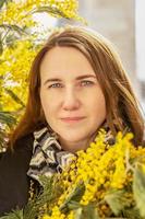 portrait d'une jeune femme avec un bouquet de mimosa dans les mains. le printemps photo