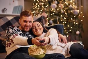 jeune couple s'embrassant à l'intérieur dans une salle décorée de noël photo