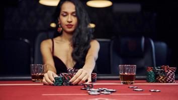 une femme en vêtements élégants est assise dans un cassino à table et joue au poker photo