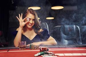 une femme en vêtements élégants est assise dans un cassino à table et joue au poker photo