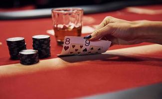 vue rapprochée des mains de la femme. fille joue au poker par table dans le casino et vérifie les cartes photo