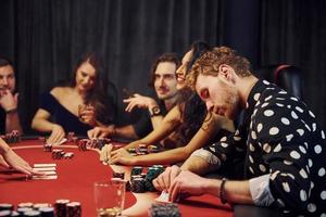 groupe de jeunes élégants qui jouent au poker au casino ensemble photo