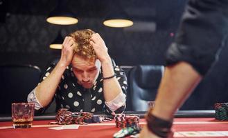 l'homme est assis dans un casino et se sent mal parce qu'il perd une partie de poker photo