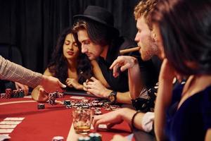 avec des verres de boisson. groupe de jeunes élégants qui jouent au poker au casino ensemble photo