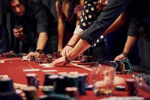 gens en vêtements élégants debout et jouant au poker ensemble au casino photo