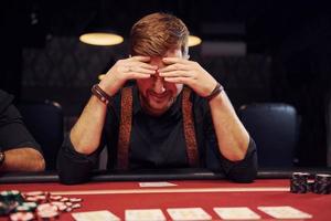 un jeune homme élégant est assis dans un casino et se sent mal parce qu'il perd une partie de poker photo