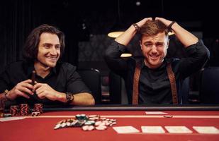 le gars perd son jeu. des jeunes élégants sont assis à table et jouent au poker au casino photo