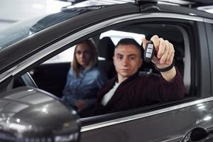 couple est assis ensemble dans la voiture. l'homme tient la voiture de l'automobile à la main photo