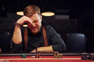 un jeune homme élégant est assis dans un casino et se sent mal parce qu'il perd une partie de poker photo