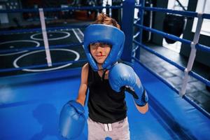 petit garçon en tenue de protection et avec formation de saignement de nez dans le ring de boxe photo