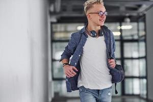 jeune étudiant en vêtements décontractés marche à l'intérieur avec sac à dos photo