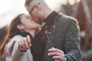 avec des cierges magiques dans les mains. heureux couple multiracial ensemble à l'extérieur de la ville photo