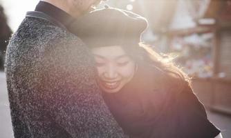joyeux couple multiracial s'embrassant à l'extérieur de la ville. fille asiatique avec son petit ami caucasien photo