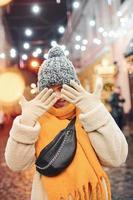 joyeuse jeune fille en vêtements chauds se promener dans la rue décorée de noël de la ville photo