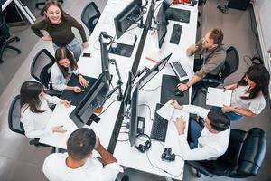 vue de dessus de jeunes gens d'affaires qui travaillent ensemble par ordinateurs dans le bureau moderne photo