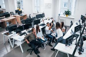 les gens parlent et travaillent ensemble dans le bureau moderne près des ordinateurs photo