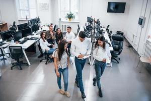 groupe de jeunes gens d'affaires debout et assis et travaillant au bureau photo