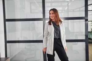 portrait de jeune femme en vêtements formels blancs qui se tient à l'intérieur photo